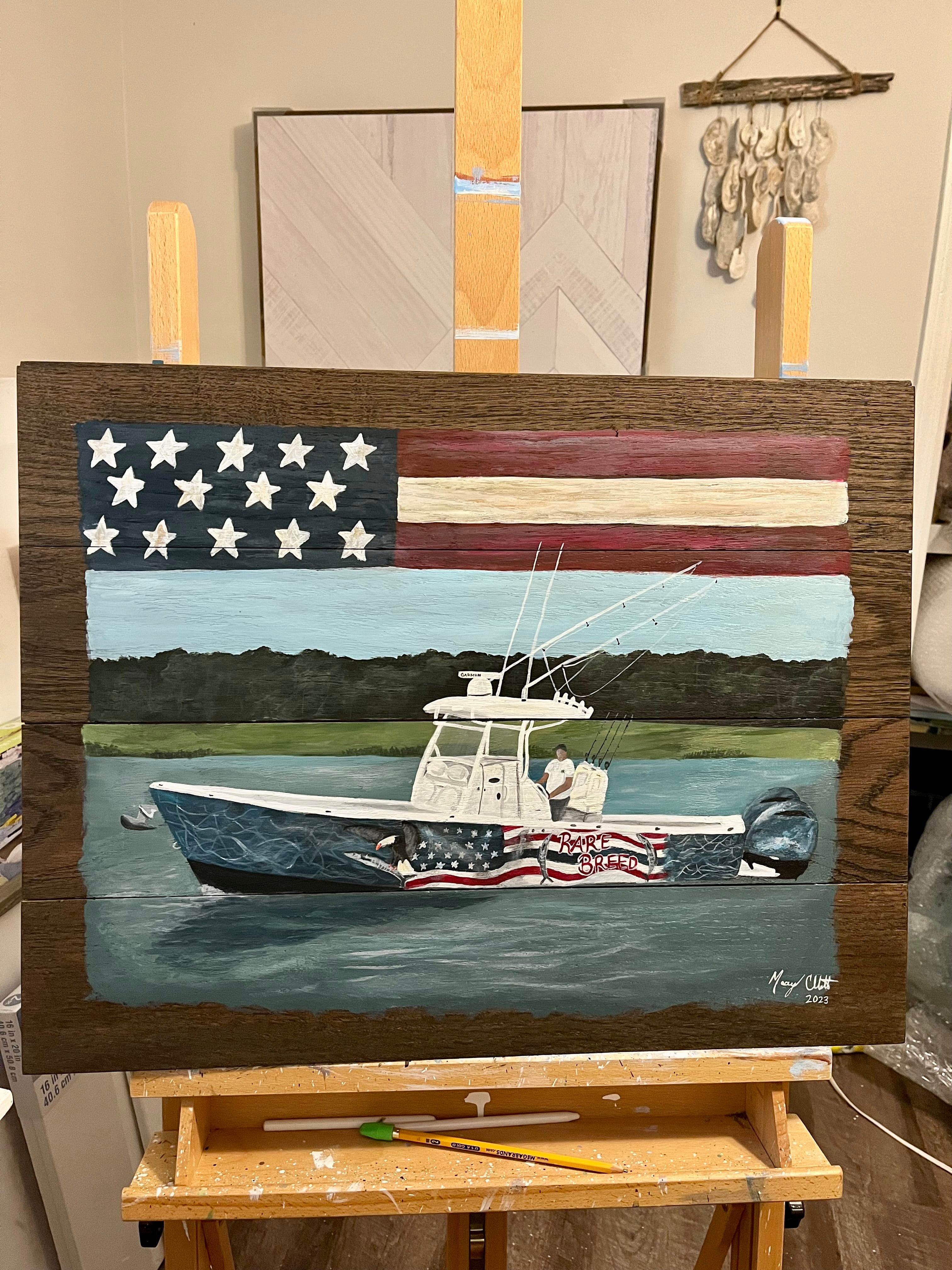 Wooden art piece with American flag design and boat on the water.